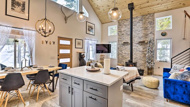 A spacious living area with a wooden ceiling, a stone wall, and a large window. - 1 Mi to St Mary’s Glacier Trail: Modern Mtn Cabin! (Idaho Springs)