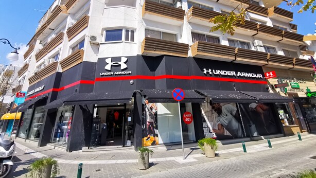 Um edifício com vários andares e uma loja Under Armour bem visível no térreo.