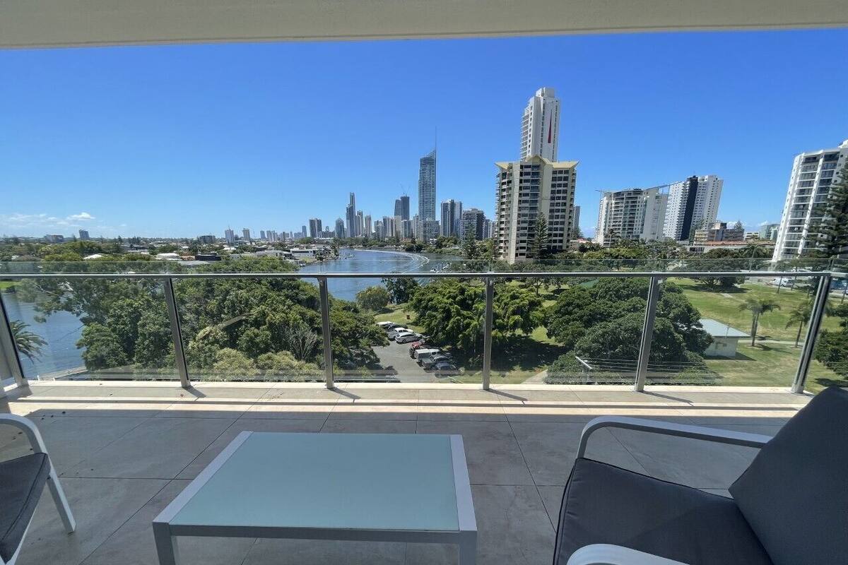 A balcony with a view of a city skyline, a table, and two chairs.