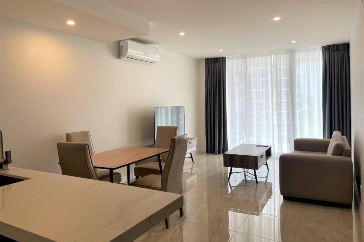 A modern hotel room with a dining area, a sofa, and a TV.