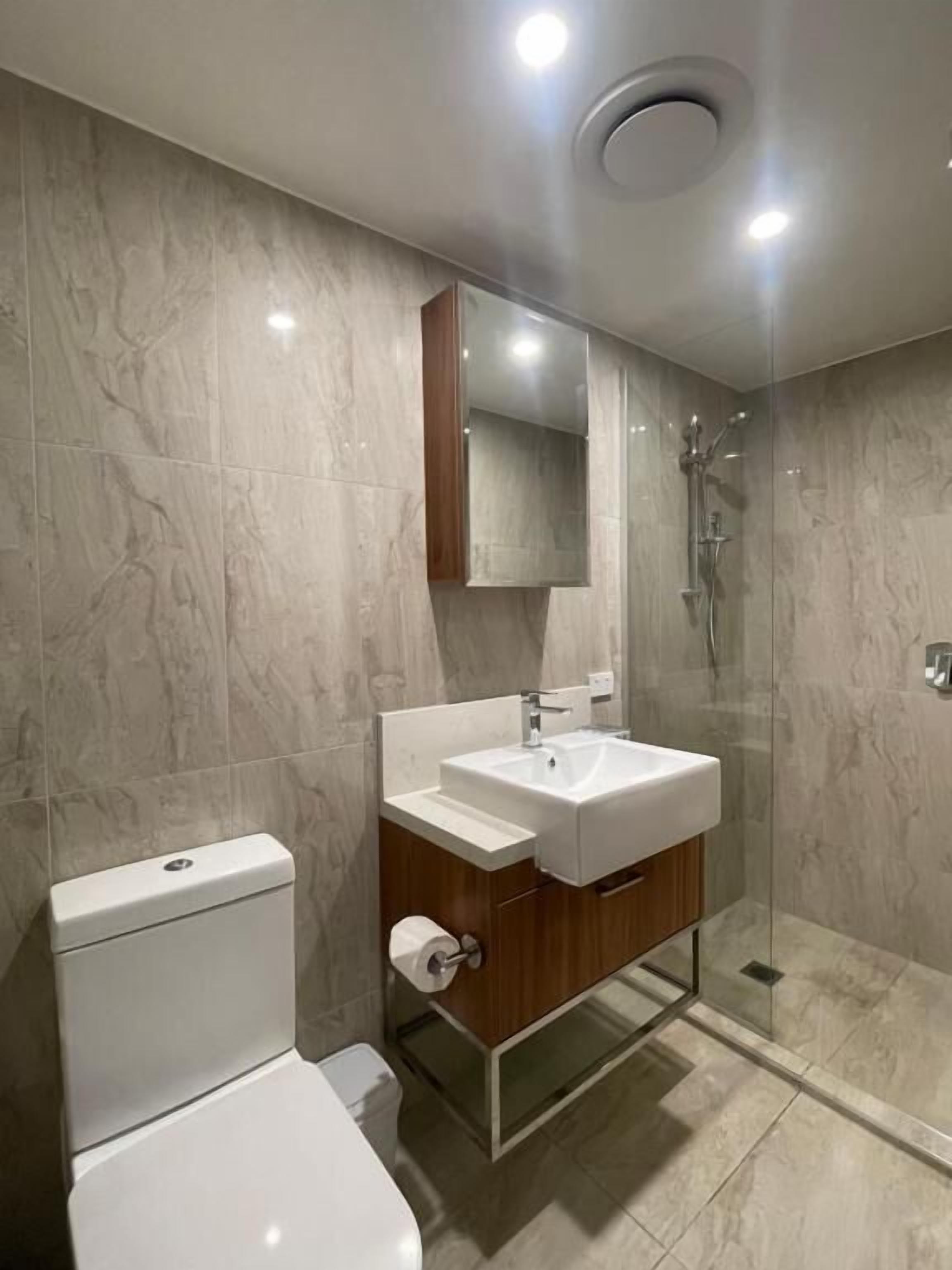 A modern bathroom with a toilet, sink, and glass-enclosed shower.