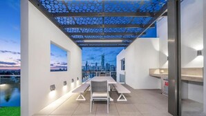 A modern outdoor dining area with a cityscape view, a pergola, and a minimalist design.