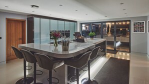 Una cocina moderna con una isla central, taburetes de bar y vistas a un comedor.