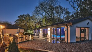Una casa moderna con piscina, cocina exterior y amplios ventanales.