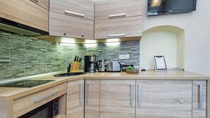 A modern kitchen with wooden cabinets, a built-in microwave, and a stone backsplash. - Select City Center Apartments Braşov (Brasov)