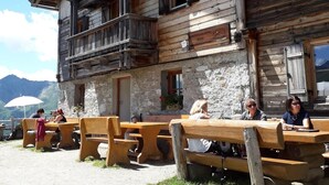 A rustic wooden building with a balcony, outdoor seating, and a stone wall. - New opening June 2022 - Chalet tree house with private whirlpool (Vandoies)