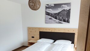 A bedroom with a wooden bed, a wall-mounted picture, and a hanging light fixture. - New opening June 2022 - Chalet tree house with private whirlpool (Vandoies)