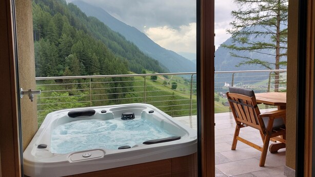 A hot tub on a balcony with a mountain view. - New opening June 2022 - Chalet tree house with private whirlpool (Vandoies)
