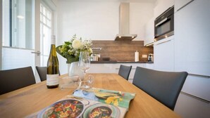 A modern dining area with a wooden table, a wine bottle, and a menu.