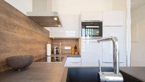 A modern kitchen with a built-in oven, stainless steel sink, and a wooden accent wall.