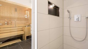 A sauna with wooden benches and a separate shower area with tiled walls and a showerhead.