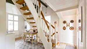 A spacious kitchen with a wooden staircase, a dining area with chairs, and a view of the outside. - Vacation home Strandschlösschen (Heringsdorf)