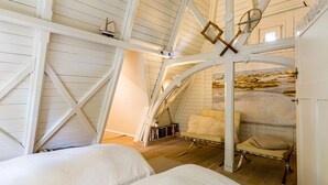 A cozy attic bedroom with a sloped ceiling, wooden beams, and a bed with white bedding. - Vacation home Strandschlösschen (Heringsdorf)