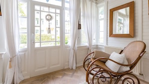 A room with a wicker chair, white curtains, and a mirror on the wall. - Vacation home Strandschlösschen (Heringsdorf)