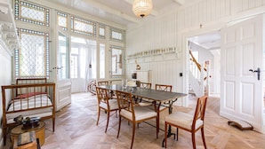 A dining room with a large wooden table, six chairs, and a chandelier. - Vacation home Strandschlösschen (Heringsdorf)