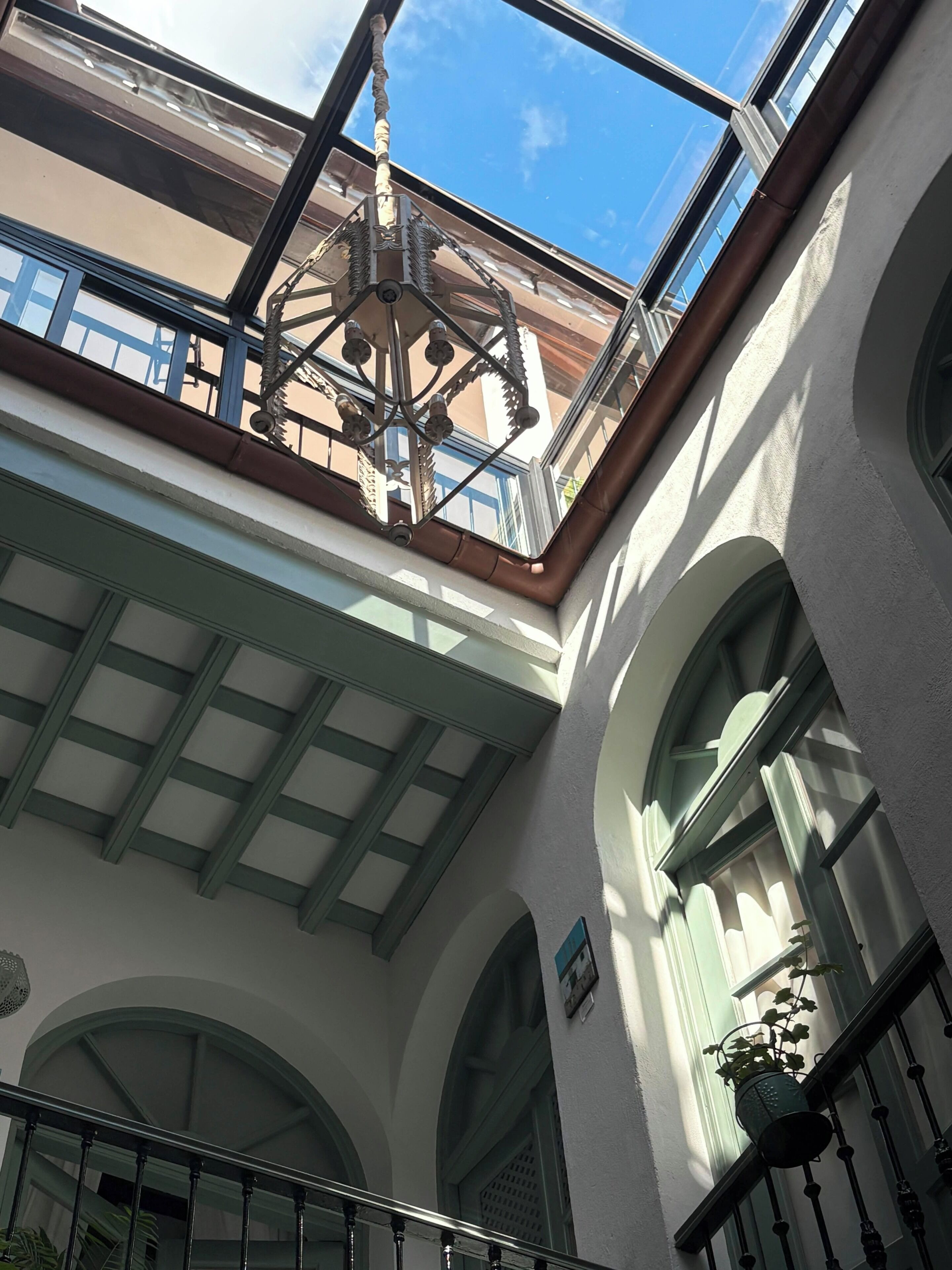 A building's interior with a skylight, arched windows, and a metal railing.