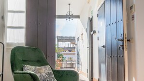 A room with a green rocking chair, a large window, and a view of a courtyard. - La Gitanilla Alojamiento & Encanto (Jerez de la Frontera)