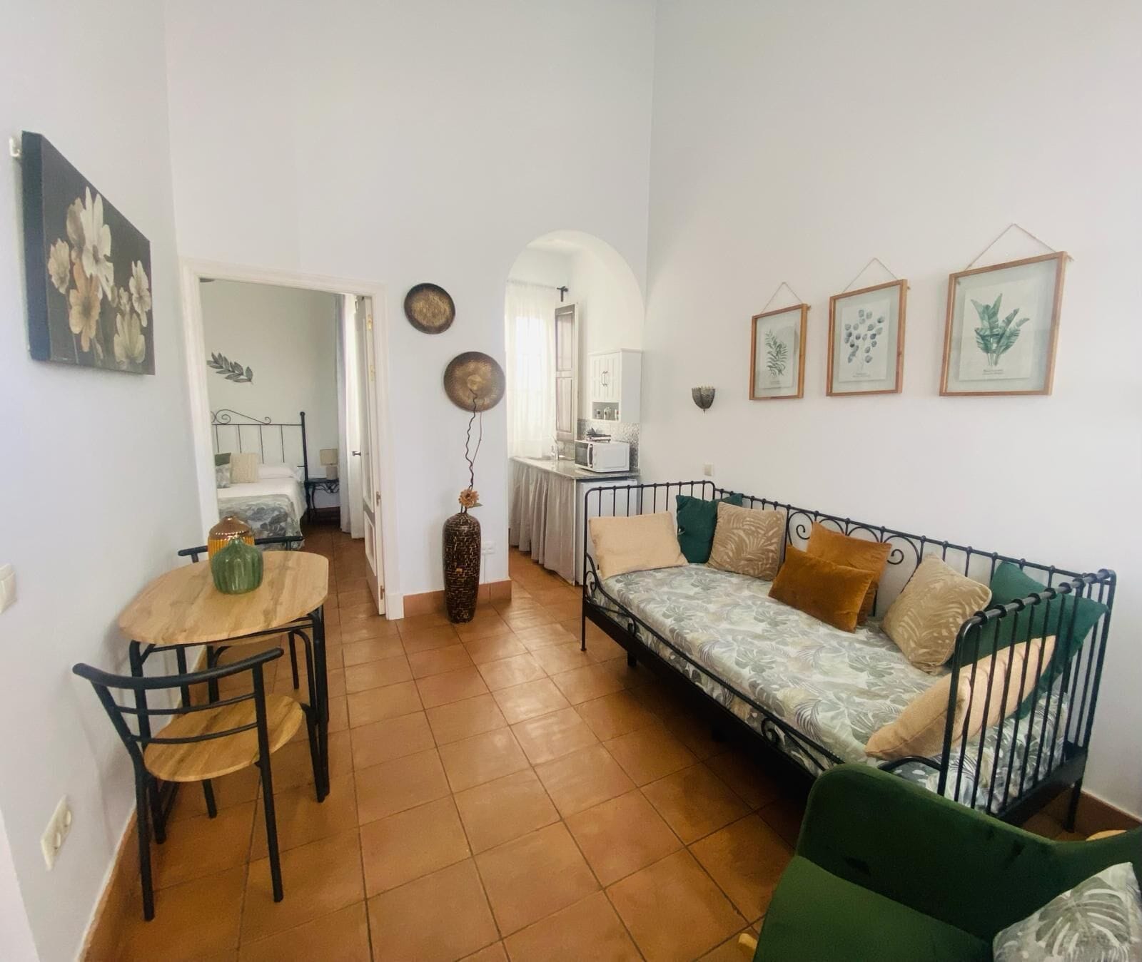 Un espacio habitable compacto con zona de comedor, sofá y kitchenette.