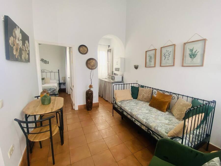 Un espacio habitable compacto con zona de comedor, sofá y kitchenette.