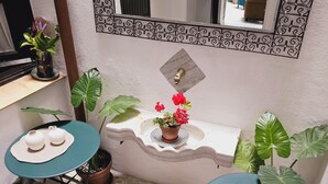A bathroom with a sink, mirror, and two small tables with decorative items. - La Gitanilla Alojamiento & Encanto (Jerez de la Frontera)
