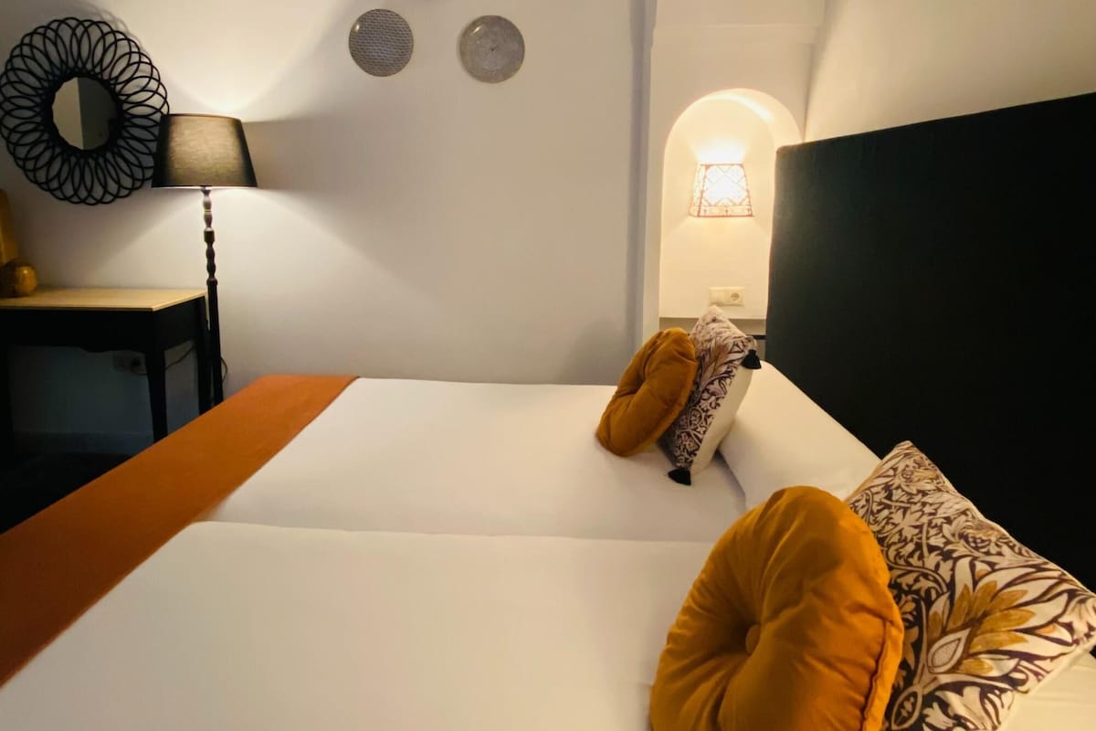 A bedroom with a bed, a desk, a lamp, and wall decorations.
