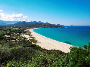 A coastal landscape with a sandy beach, a clear blue sea, and a mountainous backdrop. - Holiday Park in Corsica with Terrace Homes (Belgodere)