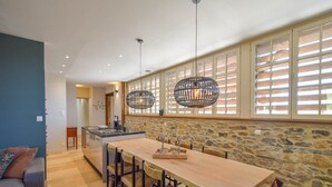 A spacious kitchen with a large island, stone walls, and a dining area with a long table and chairs.