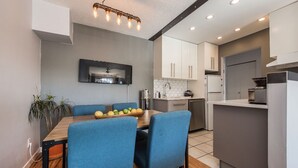 A modern kitchen with white cabinets, a built-in oven, and a dining area with blue chairs and a wooden table.