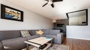 A modern living room with a grey sofa, a wooden coffee table, and a patterned rug.