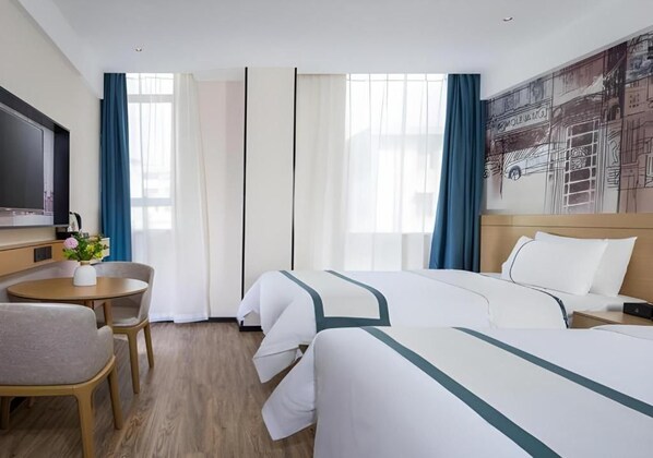 A hotel room with two beds, a desk, a chair, a TV, and a painting on the wall.