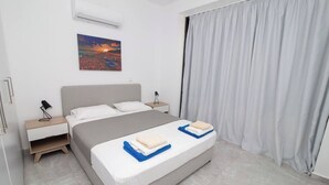 Une chambre moderne avec un lit, deux tables de chevet, une commode, un tableau et une fenêtre avec des rideaux.