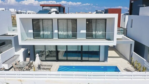 Un bâtiment moderne à deux étages, doté d’une piscine sur le toit, de grandes fenêtres et d’une balustrade en verre.
