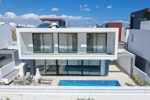 Un bâtiment moderne à deux étages, doté d’une piscine sur le toit, de grandes fenêtres et d’une balustrade en verre.