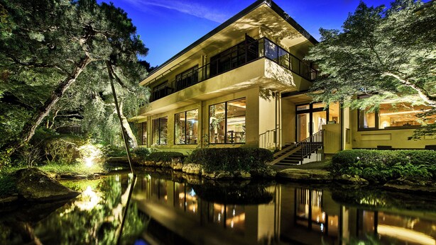 A modern two-story house with large windows, a reflection in the water, and a staircase leading to the entrance. - moksa Rebirth Hotel (Kyoto)