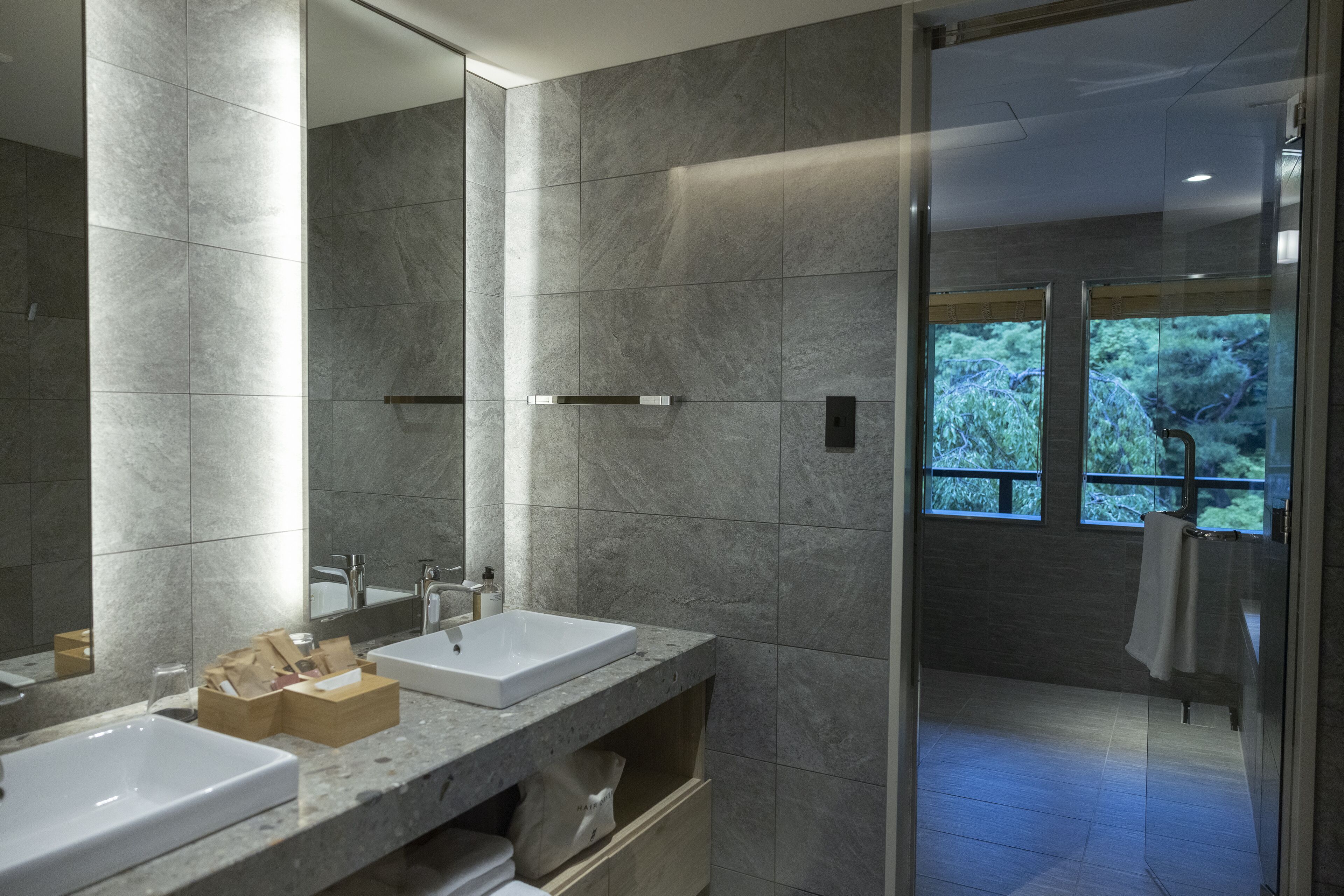A modern bathroom with two sinks, a large mirror, and a shower area with a glass door.