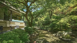 A serene garden with a koi pond, benches, and a building with large windows. - moksa Rebirth Hotel (Kyoto)