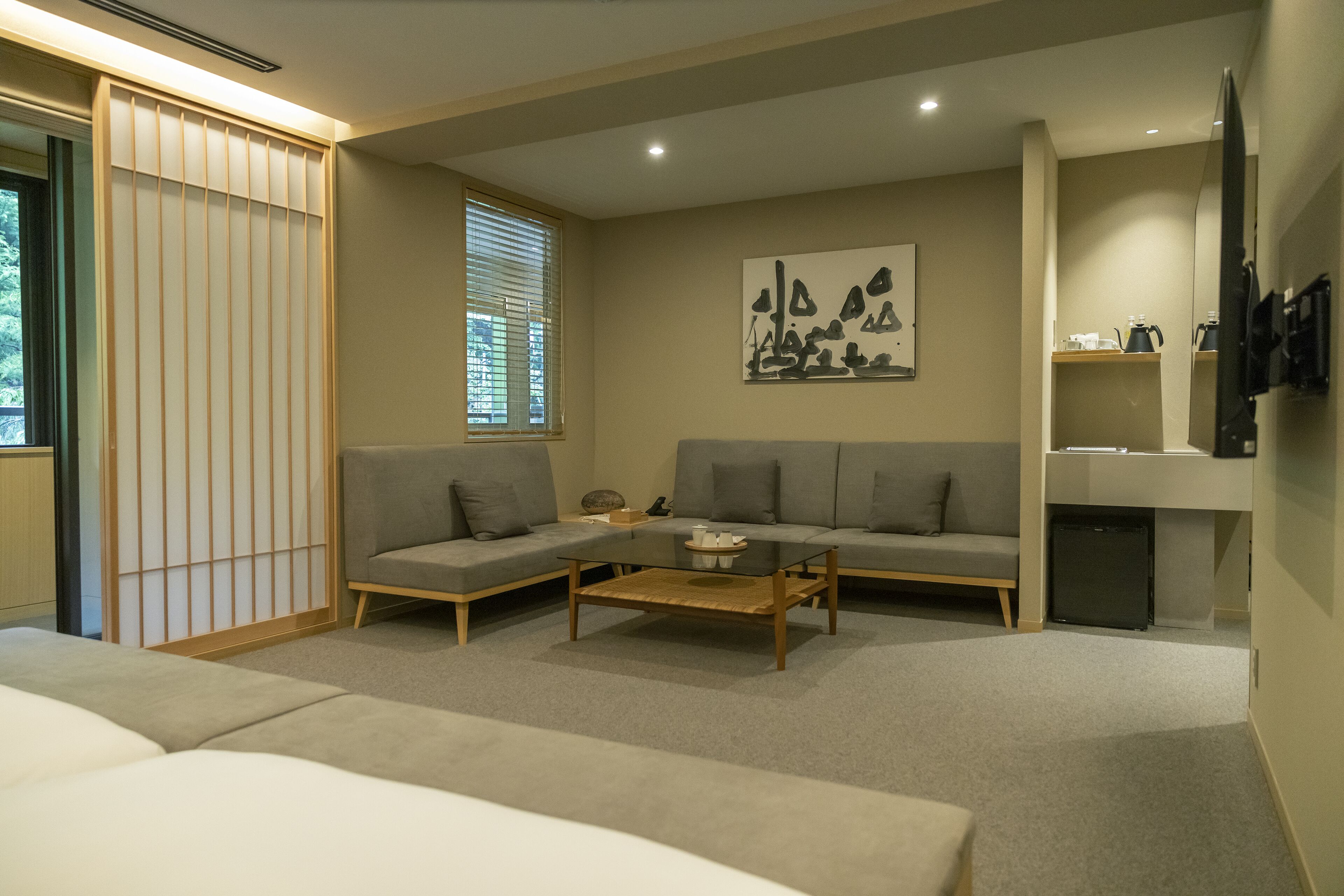 Een moderne woonkamer met een zithoek, een salontafel en een schilderij aan de muur.