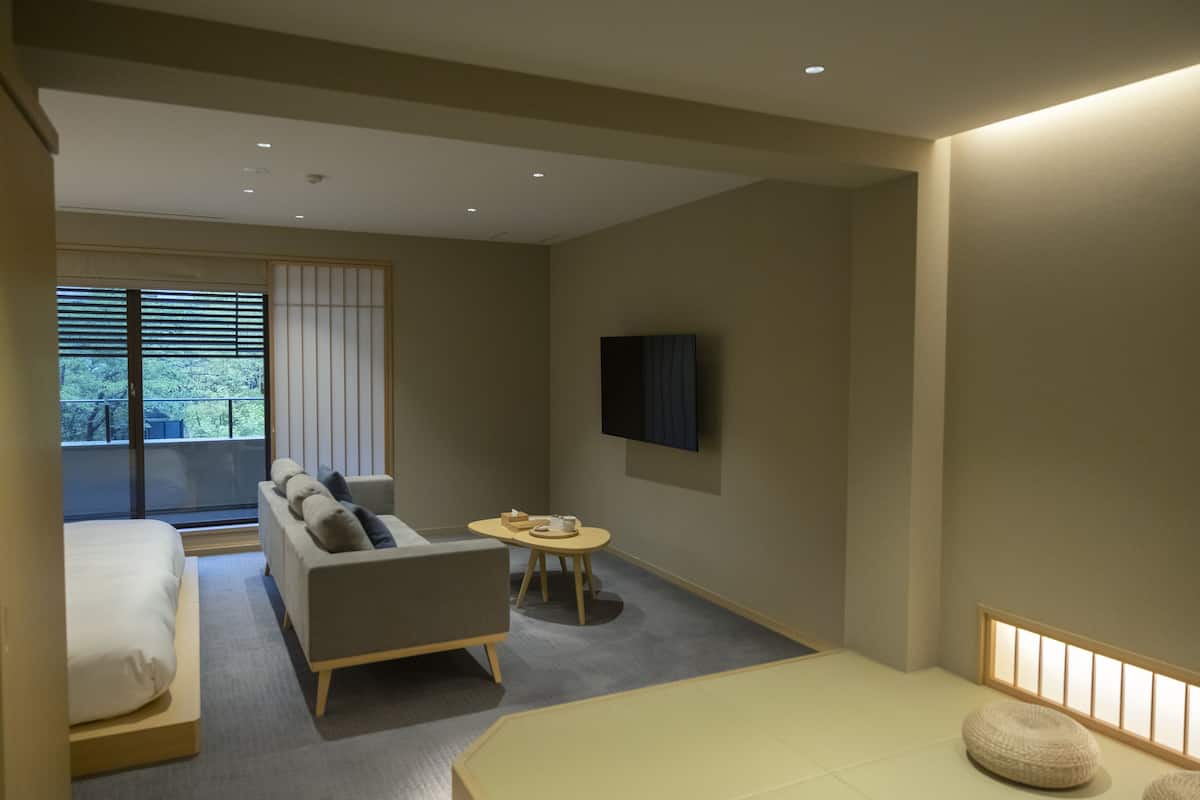 Ett modernt hotellrum med en säng, en soffa och ett litet bord.