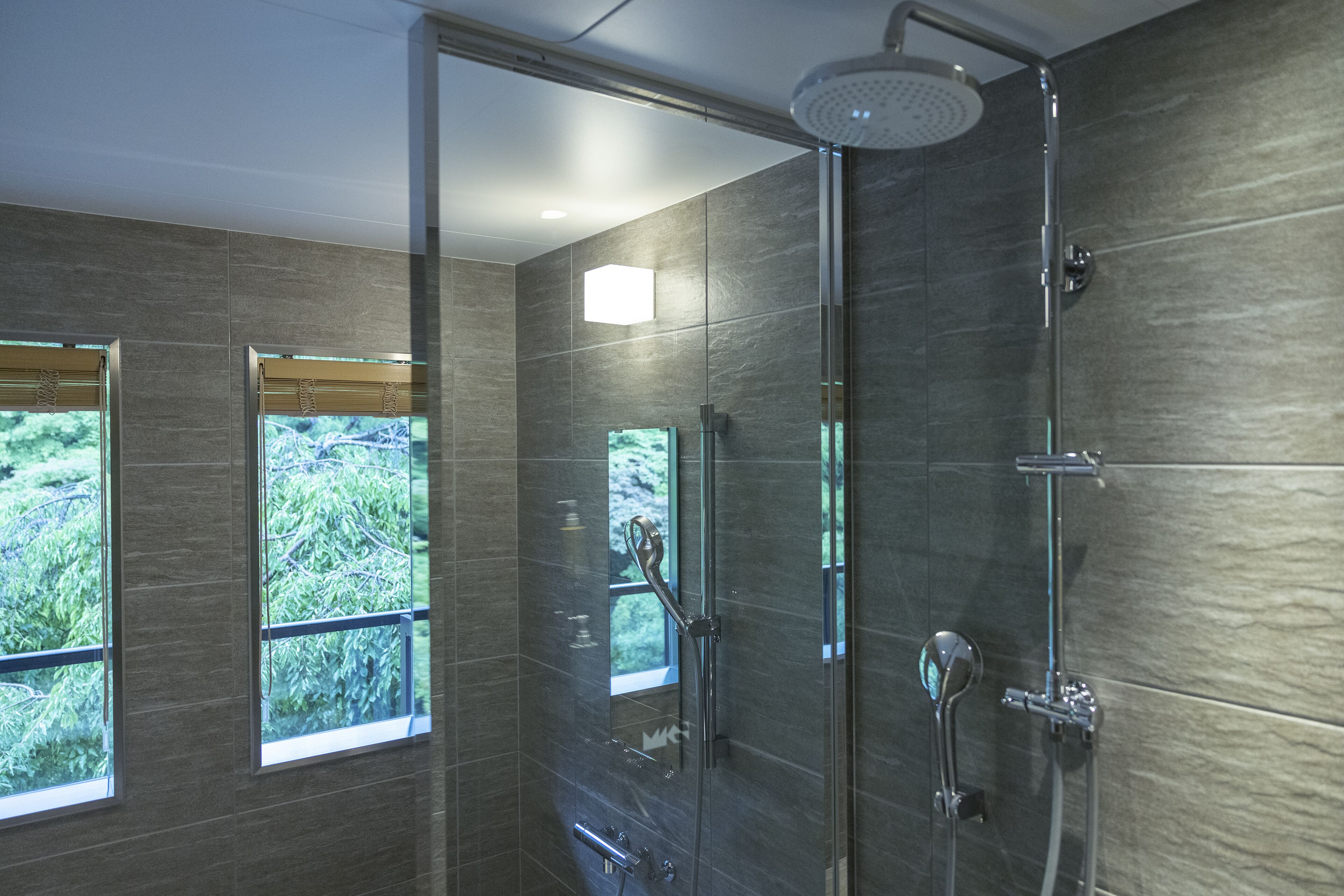 Una ducha moderna con puerta de cristal, cabezal de ducha de mano y panel de control en la pared.