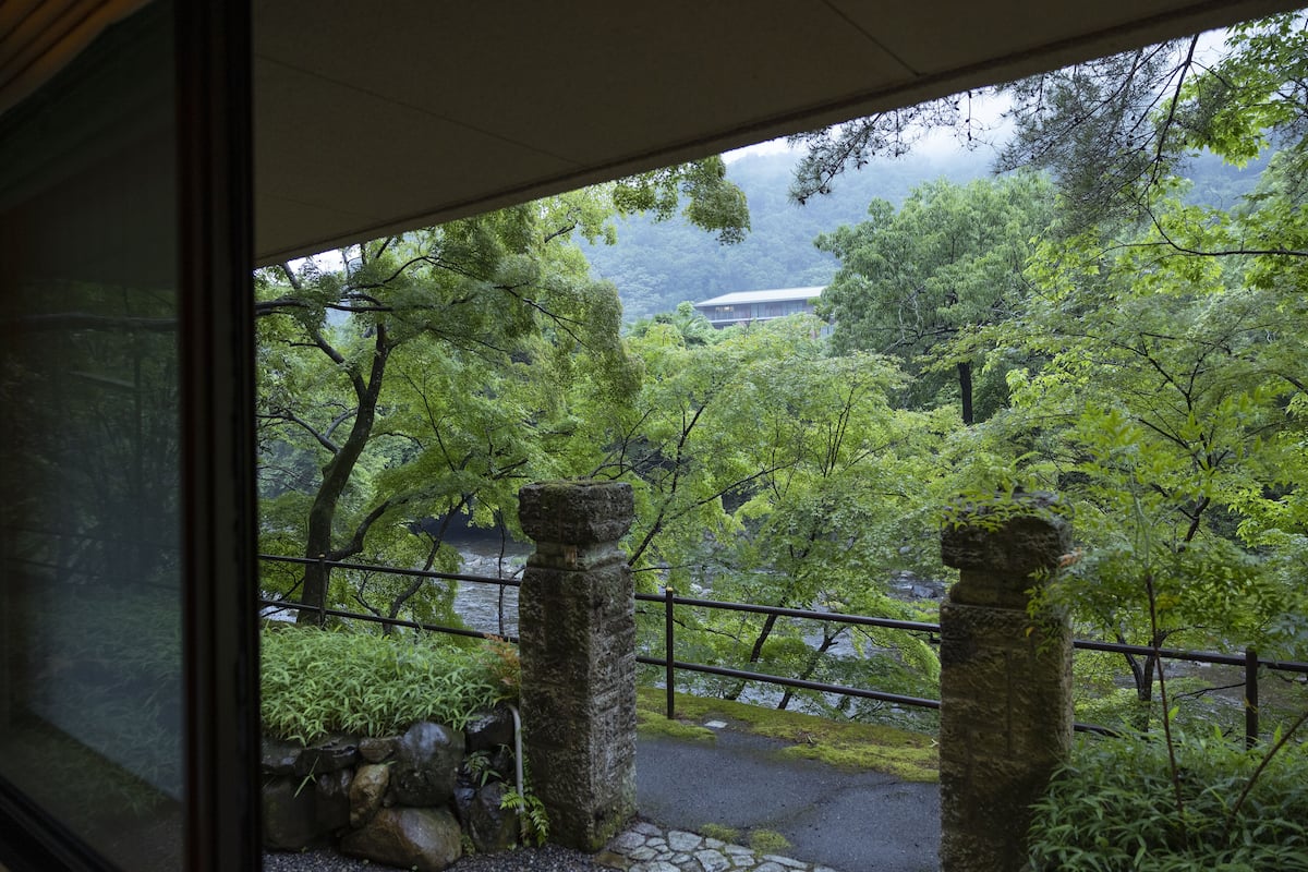 En vy över en traditionell japansk trädgård med stenlyktor, en stensatt gång och frodigt grönska.