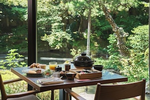 A dining table with breakfast items, a teapot, and a view of a lush garden.