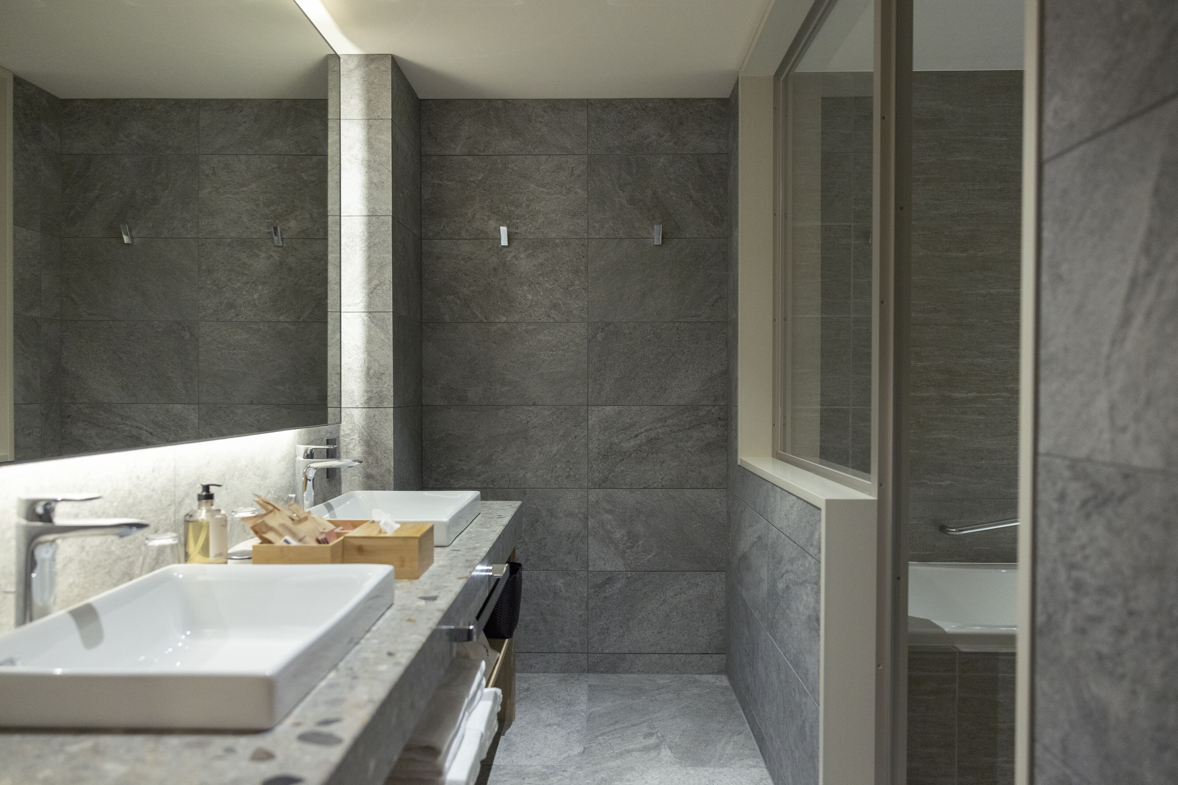 Une salle de bain moderne avec un grand miroir, deux lavabos et un espace douche.