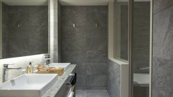 Une salle de bain moderne avec un grand miroir, deux lavabos et un espace douche.