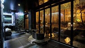 A modern spa area with a large bathtub, seating, and a view of a bamboo garden through large glass doors. - moksa Rebirth Hotel (Kyoto)