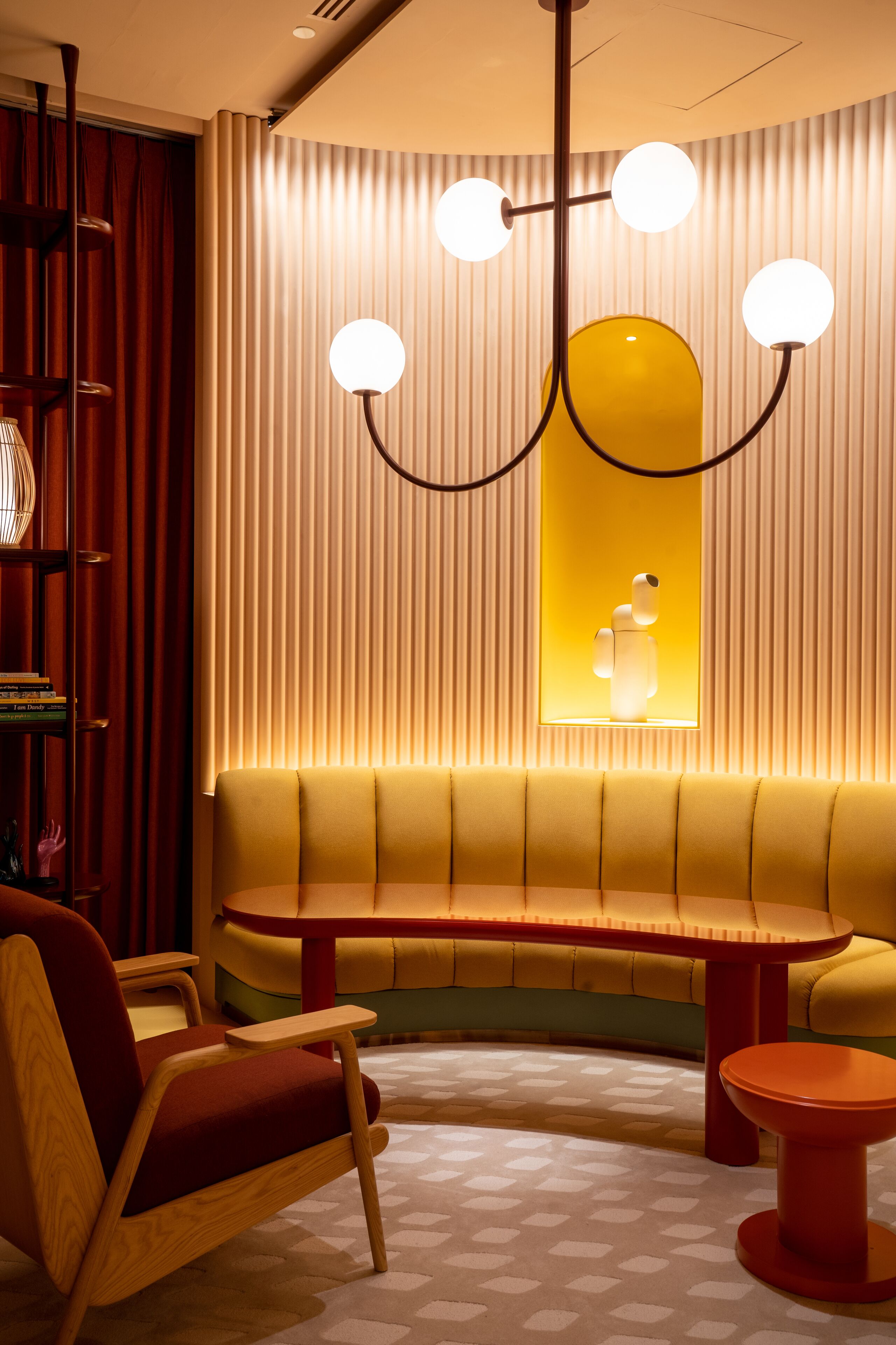 A modern interior with a curved bench, a wooden chair, and a round table.