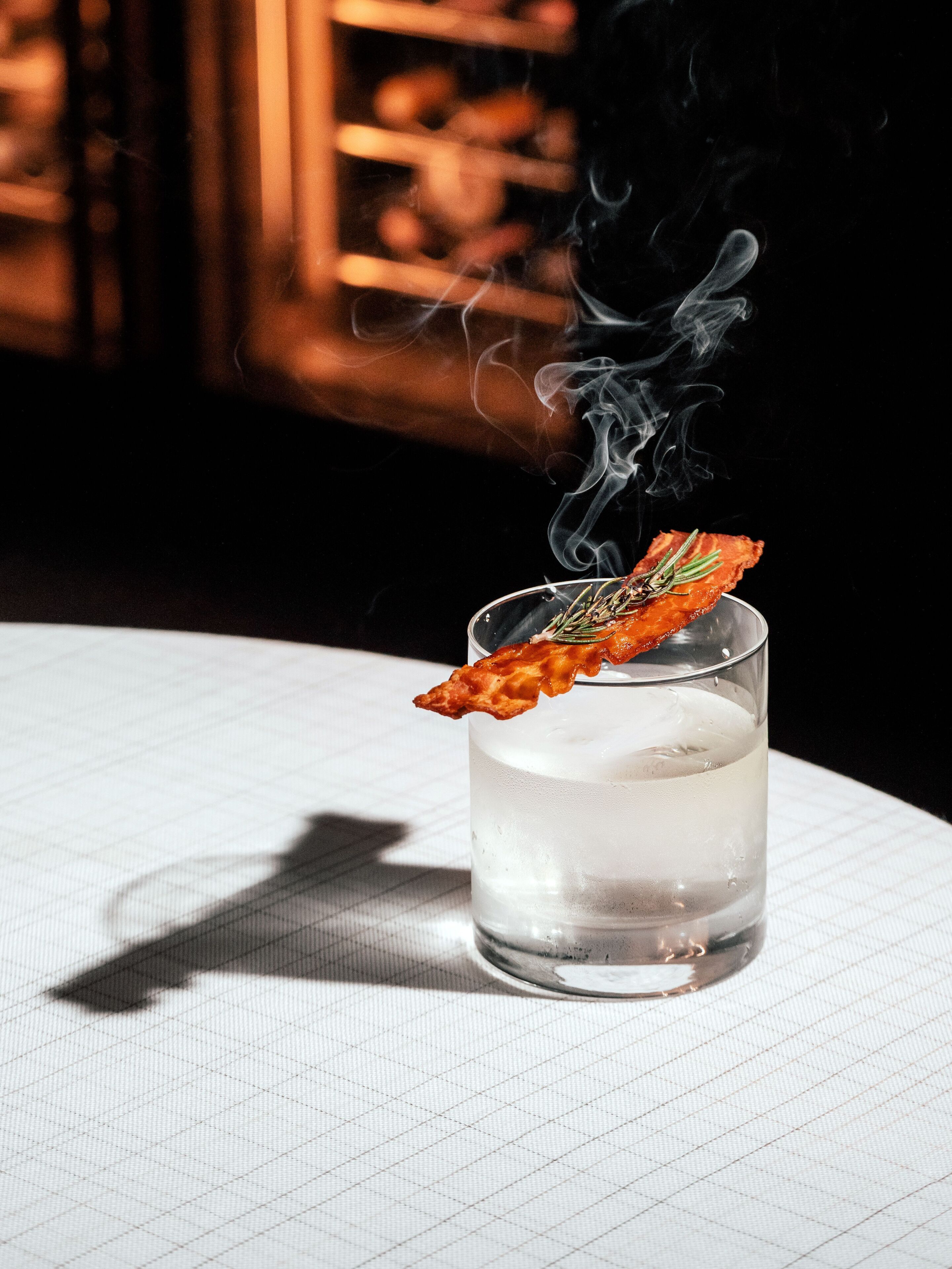 A clear glass of water with a floating garnish on a table with a grid pattern.