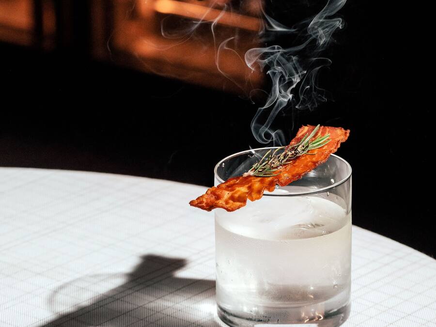 A clear glass of water with a floating garnish on a table with a grid pattern.