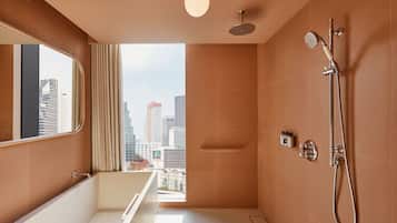 A modern bathroom with a bathtub, shower, and a large mirror.