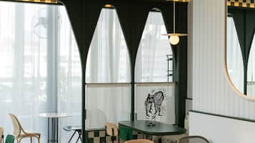 A cafe with checkered flooring, round tables, and wicker chairs.