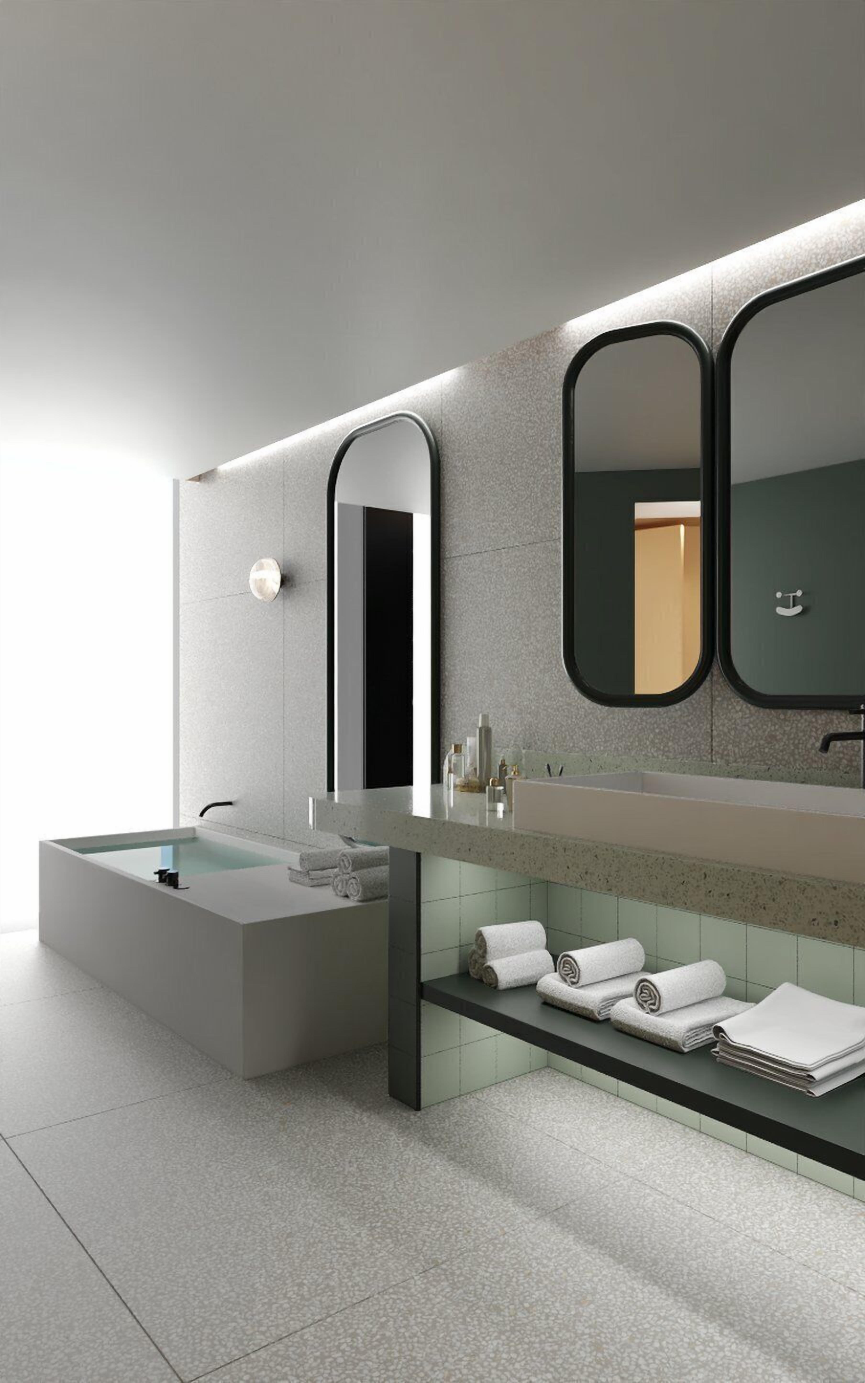 A modern bathroom with a large bathtub, a vanity with a mirror, and neatly arranged towels.